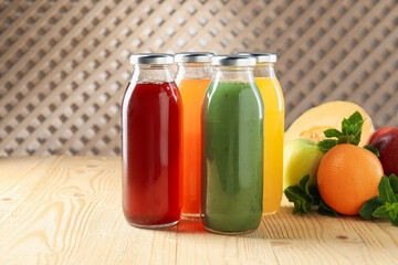 Tasty juices in glass bottles, fresh ingredients and mint on wooden table indoors, closeup