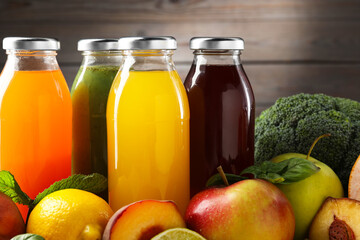 Tasty juices in glass bottles, fresh ingredients and herbs on against brown wooden background, closeup