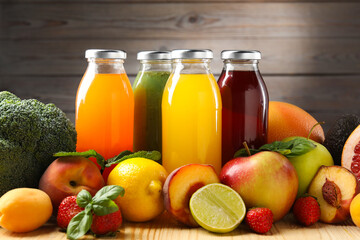 Tasty juices in glass bottles, fresh ingredients and herbs on wooden table against brown background, closeup