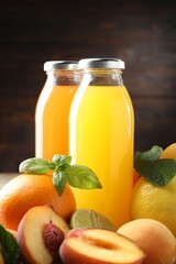 Tasty juices in glass bottles, fresh ingredients and herbs on against brown background, closeup