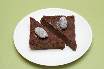 Hot date sticky pudding topped with a sugar coated date on a plate side view of Bangladeshi food