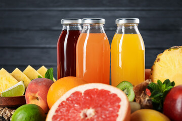 Tasty juices in glass bottles, fresh fruits and mint on table, closeup
