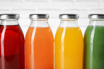 Tasty juices in glass bottles on blurred background, closeup