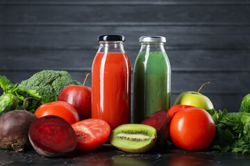 Tasty juices in glass bottles and ingredients on black marble table
