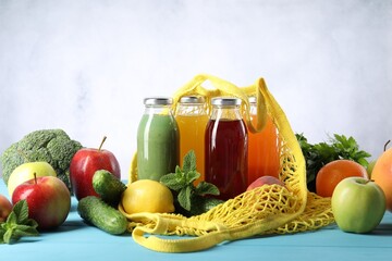 Tasty juices in glass bottles and ingredients on light blue wooden table