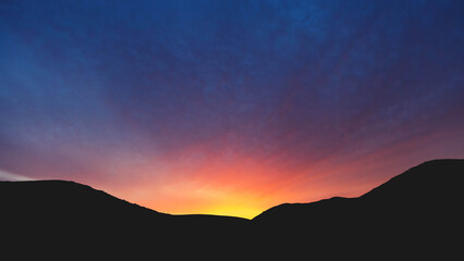 Stunning sunset over silhouetted mountains with vibrant colors and dramatic sky views
