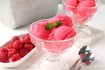 Delicious raspberry sorbet with mint in dessert bowl, spoons and fresh berries on white wooden...