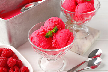 Delicious raspberry sorbet with mint in dessert bowls, spoons and fresh berries on white wooden table, closeup