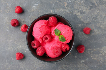 Delicious raspberry sorbet with fresh berries and mint in bowl on grey textured table, flat lay
