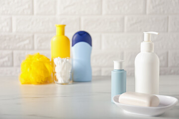 Many different baby bathroom necessities on table near brick wall, selective focus