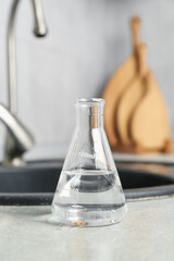 Flask with clean water near sink on counter in kitchen, closeup