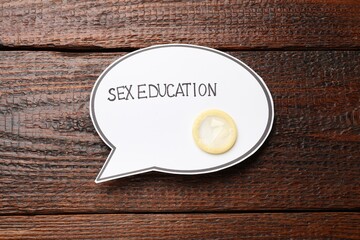 Speech bubble with phrase Sex Education and condom on wooden background, top view