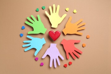 Tolerance concept. Colorful paper hands and hearts on brown background, flat lay