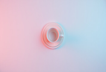 Minimalist overhead view of a clear glass teacup and saucer with soft pink and blue lighting