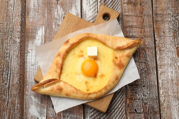 Tasty khachapuri with cheese and egg on wooden table, top view