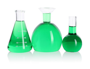 Different laboratory glassware with green liquid on mirror surface isolated on white