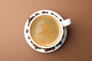 Cup of hot coffee on brown background, top view