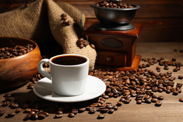 Aromatic coffee in cup, beans and grinder on wooden table