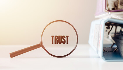 A magnifying glass with the word trust underneath it, symbolizing a focus on trust.