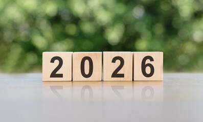 2026 on natural wooden cube highlighted by the sun, Concept to welcome the New Year 2026