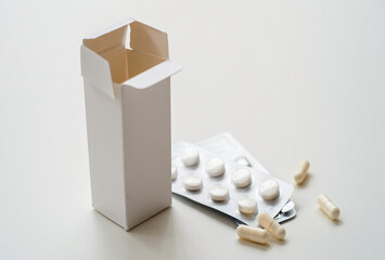 Open medicine box with blister pack of pills and scattered capsules