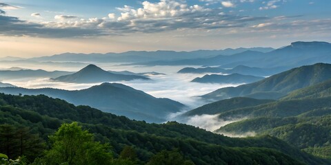 Fototapeta premium A serene mountain range with lush green forests and misty valleys under a blue sky