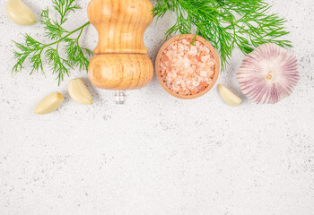 Light stone background for cooking and food preparation. Pink Himalayan salt with garlic dill and pepper mill. top view. copy space