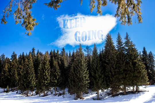Motivational winter landscape with evergreen pine forest under a bright blue sky and cloud text saying "Keep Going", symbolizing persistence, strength and determination