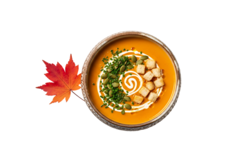 A bowl of vibrant pumpkin soup, garnished with autumnal accents,  displays a beautiful arrangement of croutons, pumpkin seeds, and chives.