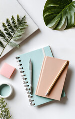 Flatlay of student essentials with notebooks, pen, leaves, and AirPods case on white desk
