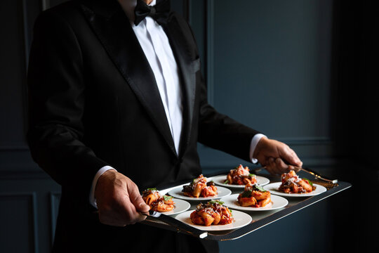 Waiter serving pasta dish from a silver tray