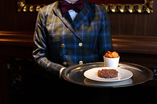 Waitress Serving Beef Tartare on a silver Tray with Potatoes