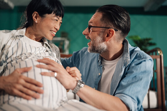 Happy couple bonding with unborn baby, pregnant woman and husband sharing intimate moment at home - Powered by Adobe