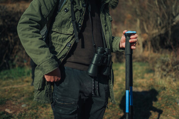 Hiker holding trekking poles and binoculars, exploring nature