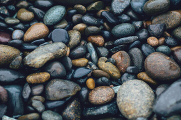 Naturally smooth wet river stones create a calming, textured background for relaxation and nature themes.