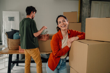 Happy couple moving into new home arranging cardboard boxes