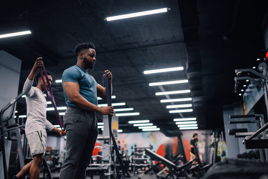 Two male athletes preparing resistance bands in gym - Powered by Adobe