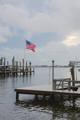 Serene waterside view showcasing a docked boat, an American flag, and surrounding greenery,...