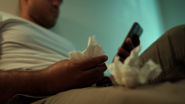 Tissues on hand Man and masturbate watching adult video on smart phone with only tissues around him. Loneliness man watching porn site video on bed.