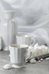 Black coffee in white porcelain cup and white small French meringues.