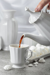 Black coffee in white porcelain cup and white small French meringues.