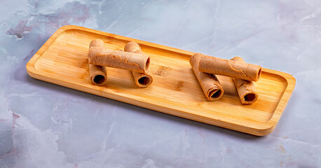 Wafer rolls on wooden tray over marble background