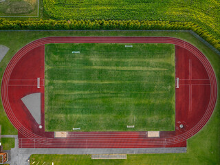 Aerial top-down view of empty Vinni Stadium, Estonia. Vibrant red running track encircles a lush...