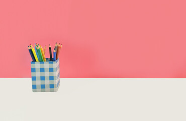 Back to school background with colorful pencils in checkered holder on white desk against pink wall, education concept for classroom, study, stationery, learning and creative workspace