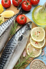 Fresh raw mackerels and spices on light blue wooden table, flat lay. Seafood delicacies