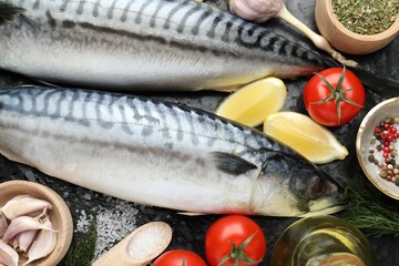 Fresh raw mackerels and spices on black table, flat lay. Seafood delicacies