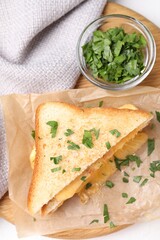 Delicious sandwich with melted cheese and parsley on white table, flat lay