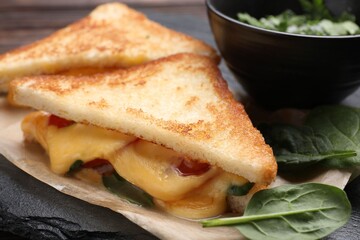 Delicious sandwiches with melted cheese and spinach on table, closeup