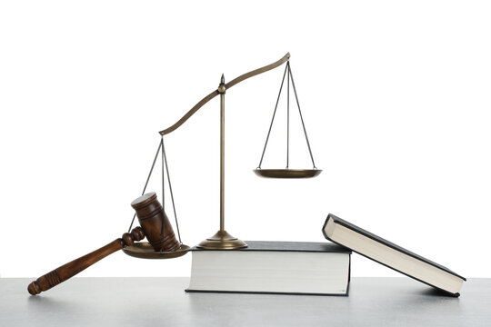 Golden scales of justice, books and gavel on light grey table against white background