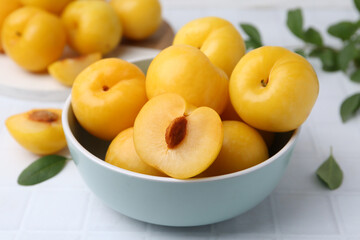 Ripe yellow cherry plums on white tiled table, closeup
